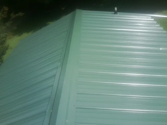 New green metal panels meeting at the ridge of a roof — Flat Roof Repair work by our crew in Downey