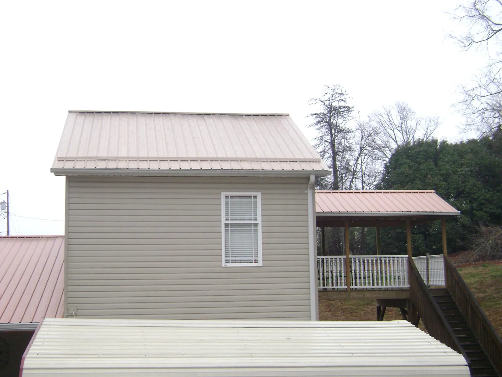 Tan metal roofs on a two story addition and attached porch, from a Roof Replacement job in Downey