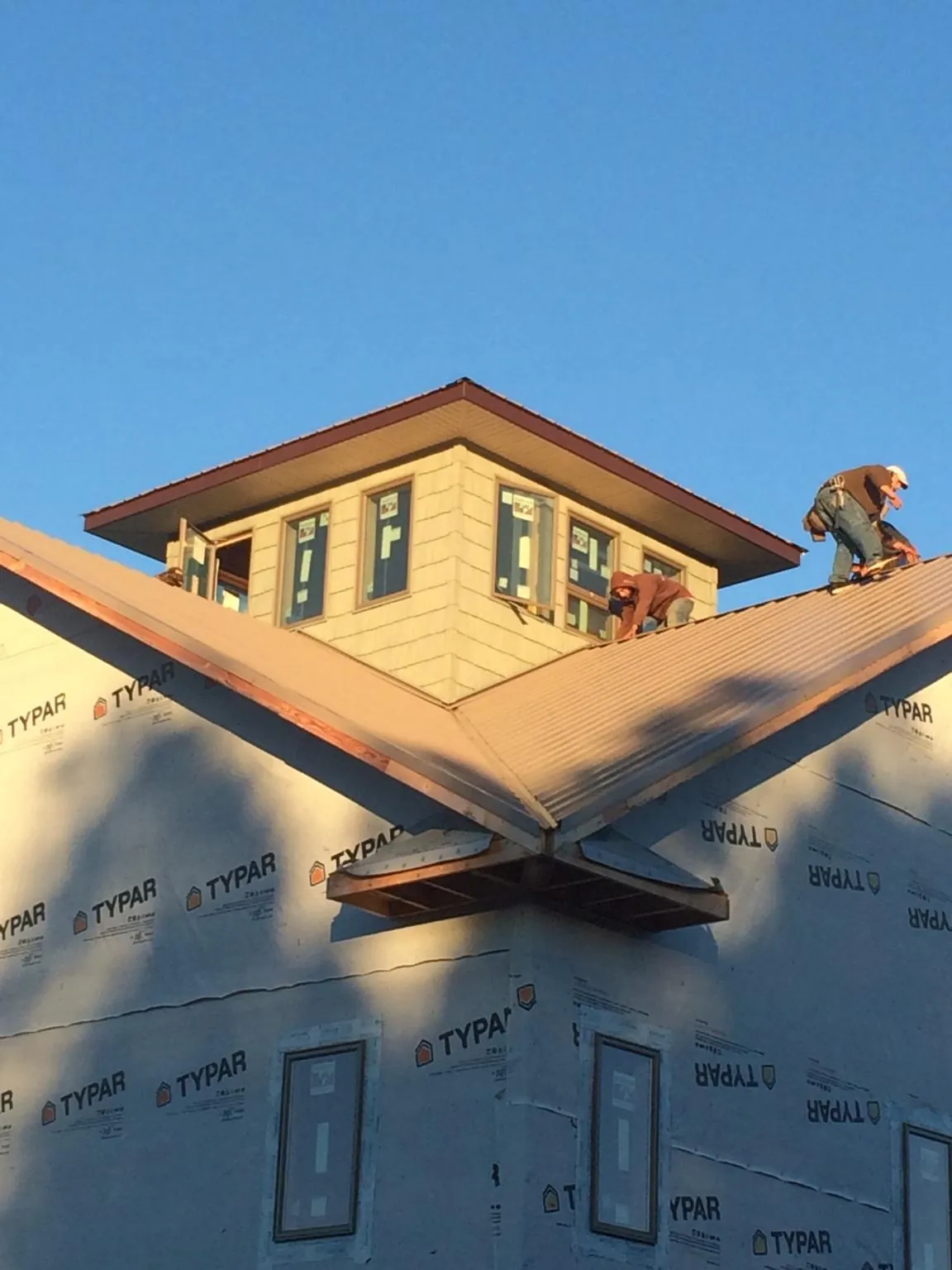 Roofers working around a rooftop cupola on a new metal roof at sunset — Roof Waterproofing in Downey by Roofing Brothers